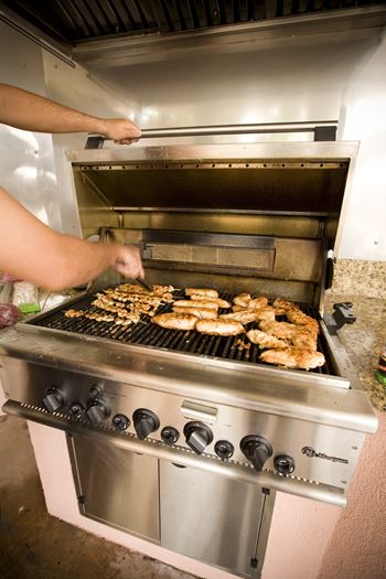 a man cooking chicken on a grill